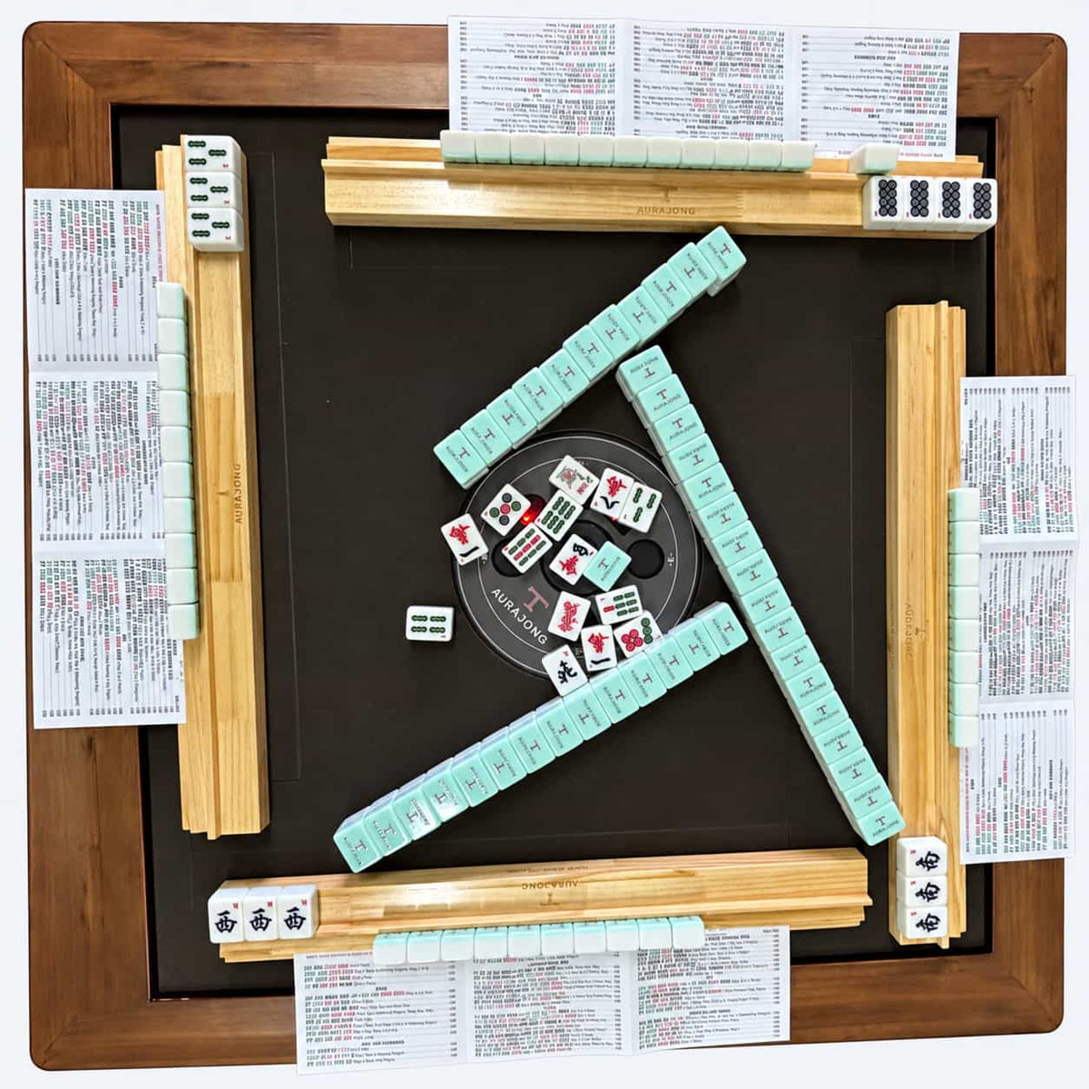 Top view of the AURAJONG R1 automatic American Mahjong table during play with tiles, Sightline Racks, and NMJL cards