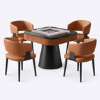 AURAJONG R5 automatic American Mahjong table set with a grey play surface, pink mahjong tile walls, walnut-tone table body, black pedestal base, and four cognac upholstered chairs.