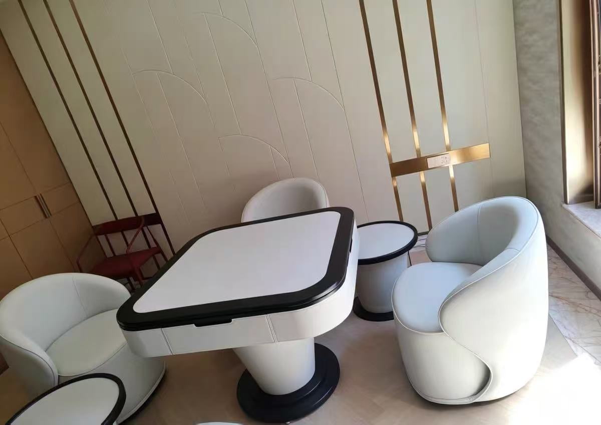 AURAJONG S1 automatic American Mahjong table with ivory finish, black trim, and four upholstered lounge chairs in a modern interior