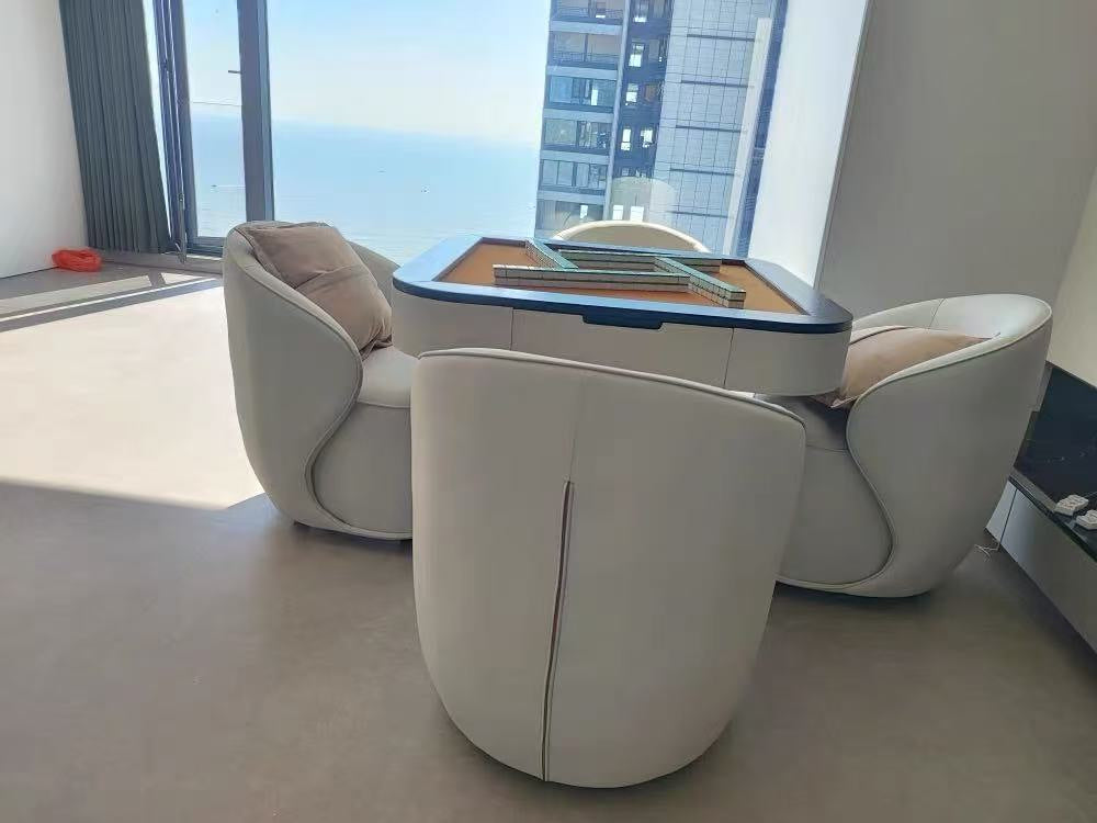 AURAJONG S1 automatic American Mahjong table with exposed Mahjong play surface and four ivory lounge chairs in a bright window-side setting