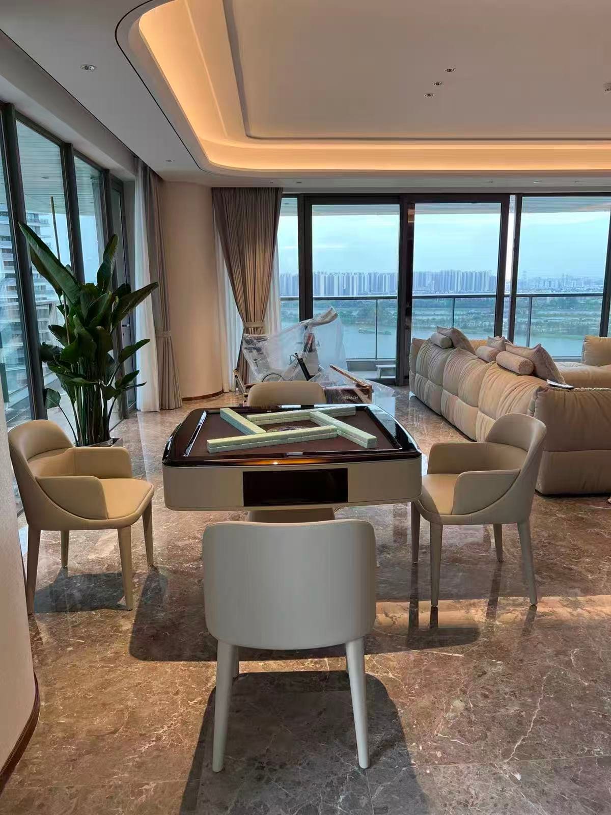 AURAJONG S3 automatic American Mahjong table with open Mahjong play surface in a luxury living room with cream upholstered chairs and city views